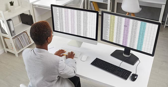 Woman quickly entering data sets on two computer monitors using the Excel fill handle