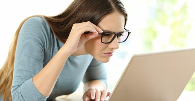 Women holding her glasses up close to a computer screen and reading about how to select every other row in Excel